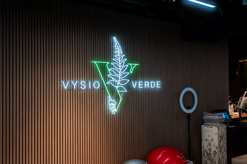 Neonschild Vysio Verde in Gruen und Weiss mit Blattlogo an Wand