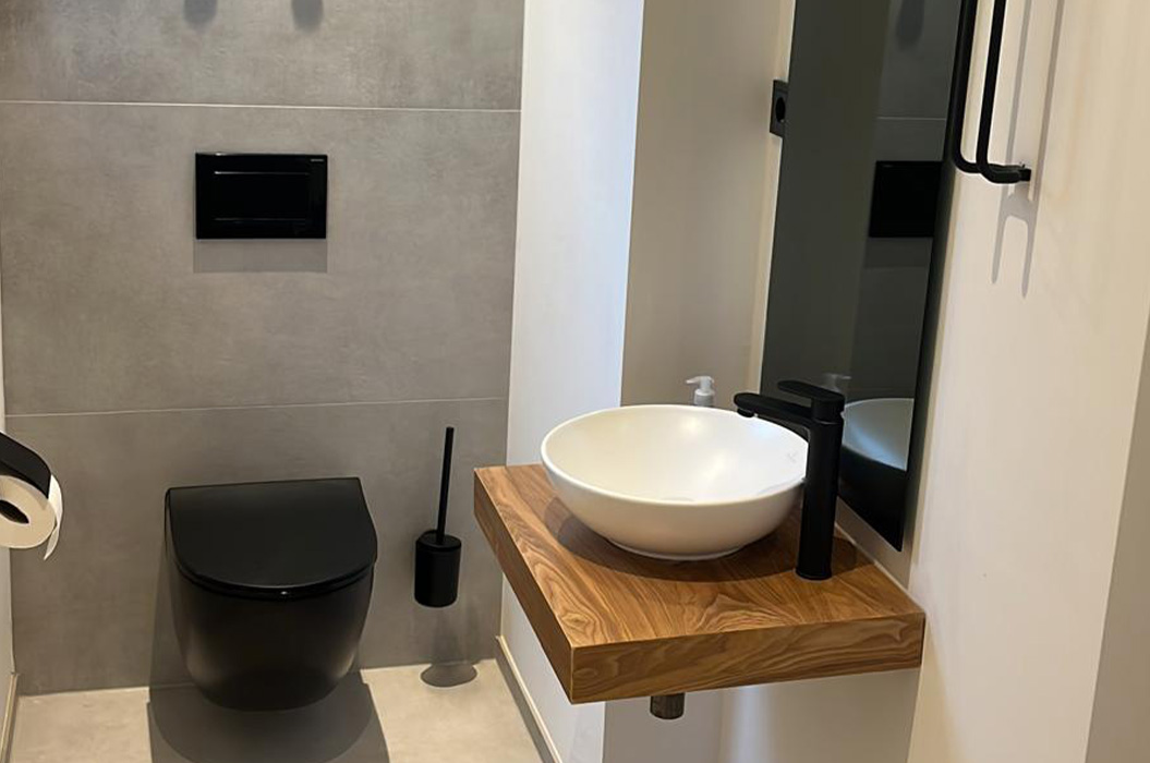Modernes Bad mit schwarzem WC und rundem Waschbecken auf Holzplatte