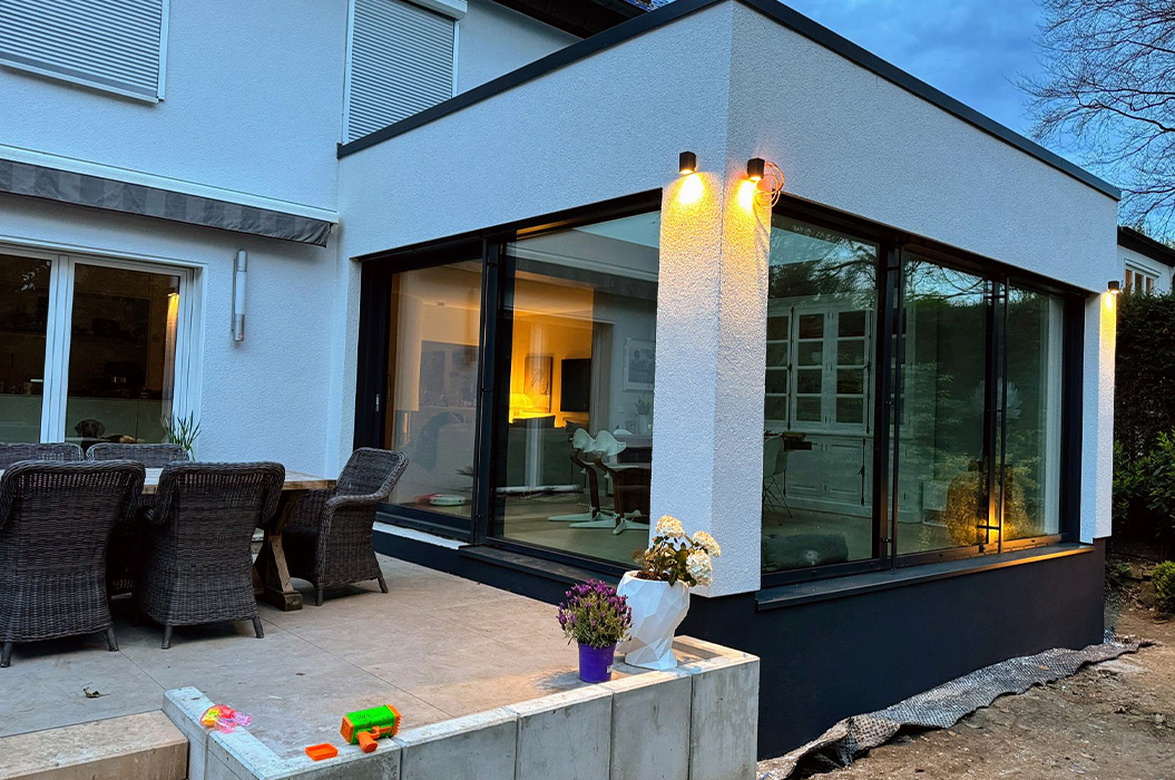 Modernes Haus mit Glaswintergarten in Weiss Schwarz und beleuchteten Lampen