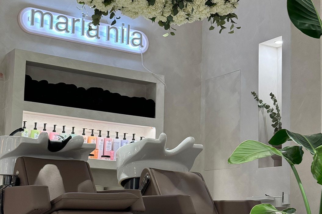 Moderner Friseursalon mit zwei grauen Waschstuehlen und leuchtendem Schild in Blau