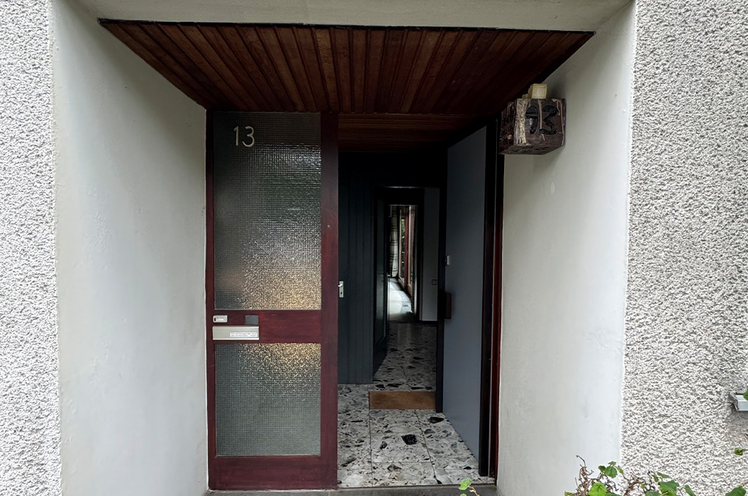 Offene Haustuer mit matte Glas, dunklem Rahmen, Nummer 13 und Lampe, ruhig