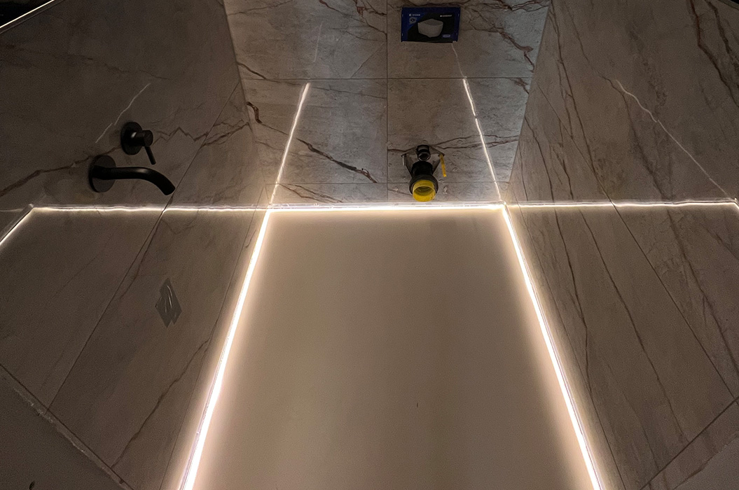 Leere Duschkabine in Grau mit LED Linien und schwarzem Wasserhahn