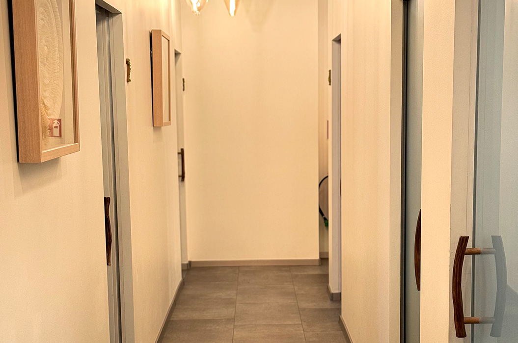 Leerer heller Flur mit grauen Fliesen und Holztueren, warmes Licht
