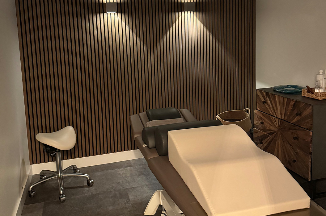 Leerer Behandlungsraum in Braun und Beige mit Liege und Holzlamellenwand