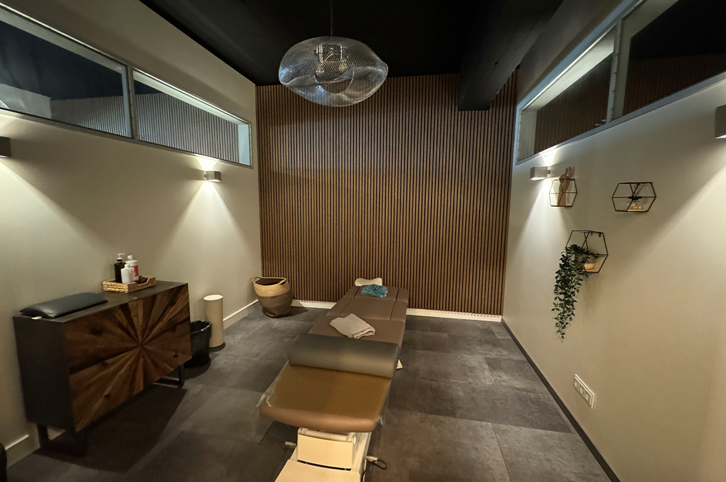 Ruhiger Massageraum in Beige und Grau mit Liege und Holzwand