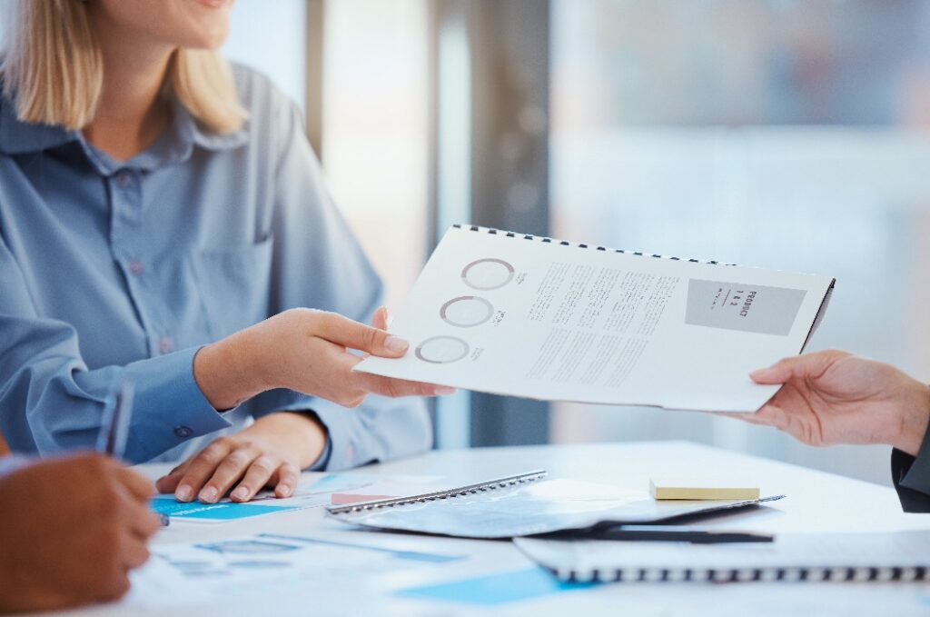 Hand, Dokument und Besprechung mit dem Marketingteam bei der gemeinsamen Durchsicht eines Berichts, eines Vorschlags oder von Unterlagen am Tisch. Teamarbeit, Zusammenarbeit und Unterstützung in einem Finanzworkshop mit Geschäftsleuten eines Start-up-Unternehmens