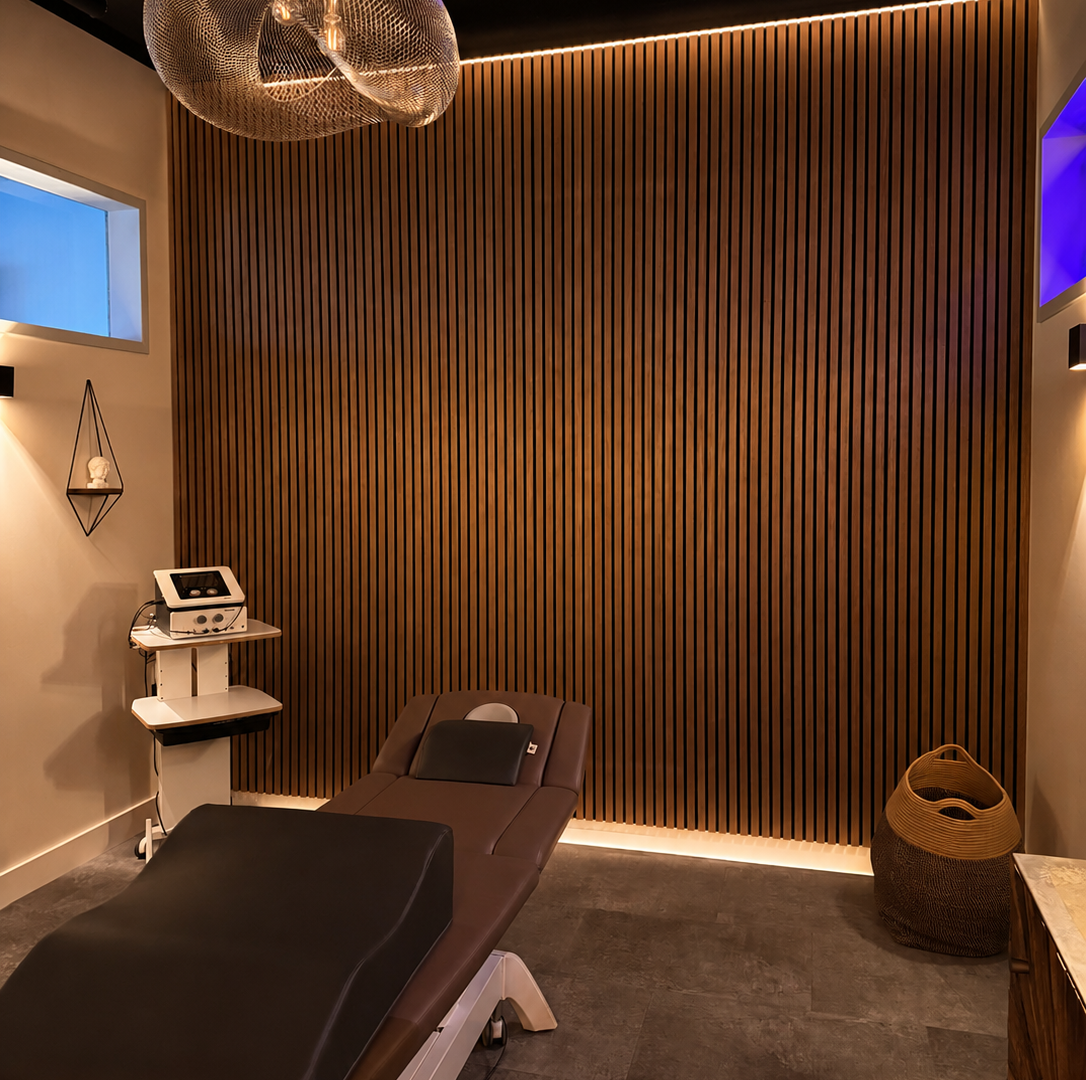 Moderner Behandlungsraum mit Massageliege Holzwand und stimmungsvollem Licht